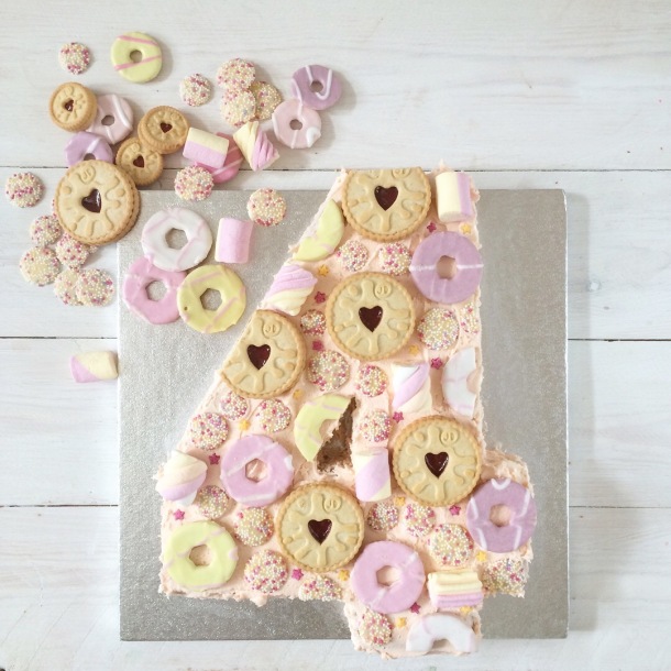 Pink number 4 cake with strawberry milkshake buttercream icing and topped with jammy dodger biscuits, party rings, marshmallows and jazzies